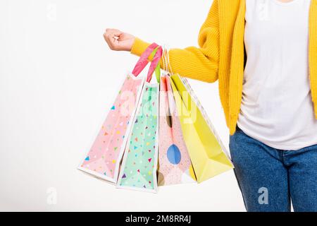 donna mano indossa una camicia gialla che tiene borse di shopping multicolore Foto Stock