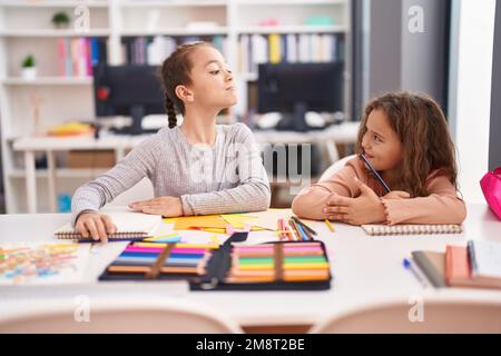 Due studenti bambini seduti sul tavolo disegnando su un foglio di carta in classe Foto Stock