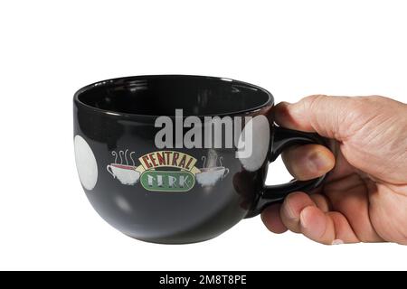 Vista ravvicinata della mano dell'uomo che tiene in mano una grande tazza nera ricordo con il logo di Central Perk della famosa serie Friends. Svezia. Foto Stock