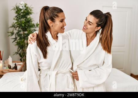 Due donne che indossano un accappatoio che si abbraccia in piedi presso il centro di bellezza Foto Stock