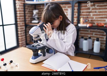 Adorabile ragazza ispanica studente utilizzando il microscopio in laboratorio classe Foto Stock