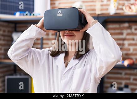 Adorabile ragazza ispanica studente utilizzando occhiali di realtà virtuale in classe laboratorio Foto Stock