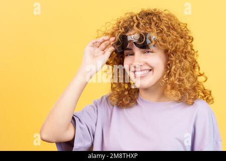 Donna che solleva gli occhiali da sole e guarda la fotocamera Foto Stock