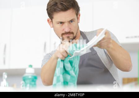 giovane uomo asciugando e lucidando piatto con un asciugamano Foto Stock