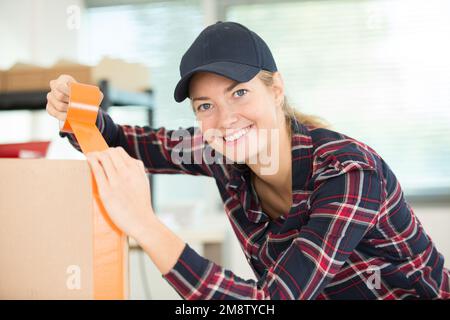 giovane donna che avvolgono una scatola di cartone Foto Stock