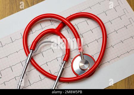 Primo piano dello stetoscopio a cuore rosso su carta per elettrocardiogramma (ECG) Foto Stock