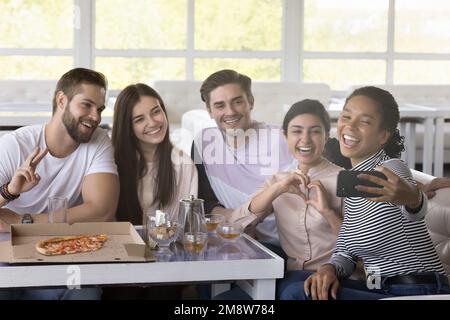 Amici multietnici felici che prendono selfie su smartphone in caffè Foto Stock