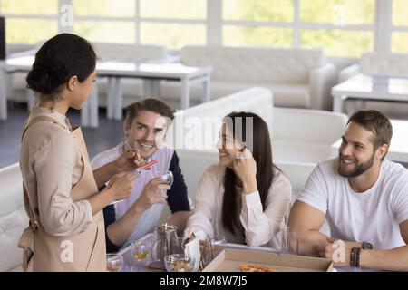 Cameriera indiana che ascolta il gruppo di clienti felici nel caffè Foto Stock