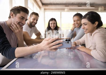 Allegri compagni di squadra multietnici che si riuniscono al tavolo del caffè Foto Stock