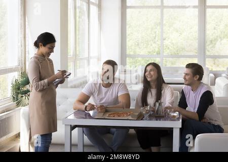 Positivo amichevole bella cameriera indiana con grembiule Foto Stock