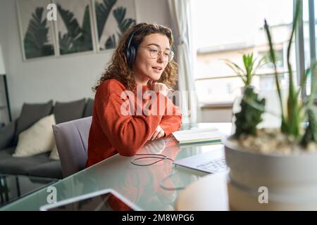 Una giovane donna che guarda il webinar elearning utilizzando il computer a casa. Foto Stock