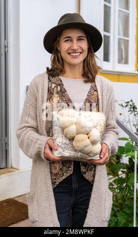 Giovane donna sorridente che tiene coltivato medio con funghi di criniera di leone Foto Stock