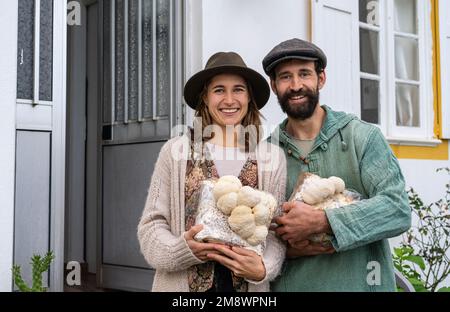 Coppia contadina carina che tiene blocchi di funghi di criniera leone Foto Stock