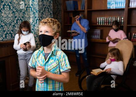 Tween ragazzo in maschera di protezione risolvere puzzle in camera di fuga Foto Stock