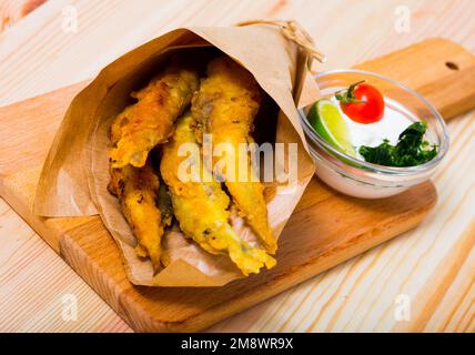 Acciughe fritte in padella con salsa cremosa al formaggio, verdure Foto Stock