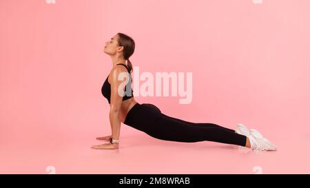 Giovane donna sportiva che pratica lo yoga in interni, rendendo il cane rivolto verso l'alto posa Foto Stock