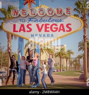 Gruppo di turisti che saltano per una foto all'iconico cartello Welcome to Fabulous Las Vegas su Las Vegas Boulevard risale al 1959. Foto Stock