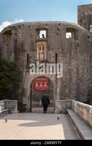 Uomo anziano che cammina attraverso l'ingresso porta pile alla città vecchia di Dubrovnik, Croazia Foto Stock