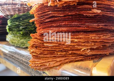 Pile di Tklapi - pastila tradizionale georgiana o pelle di frutta. Colorati fogli di frutta secca di funghi venduti al mercato alimentare per i turisti. Delizioso e. Foto Stock