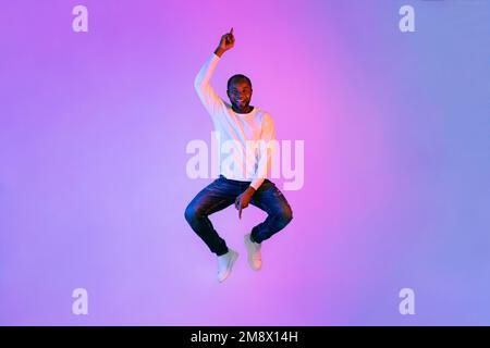 Divertente uomo afroamericano che salta in aria e gesturing Foto Stock