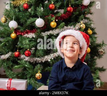 Bambino che indossa il cappello di santa sorridendo guardando al lato e fissando via pensando. Foto Stock