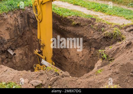 Il pistone dell'escavatore idraulico scava in profondità nell'area industriale del cantiere. Foto Stock