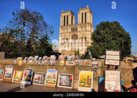 Parigi: Arte in vendita sul Petit Pont sulla Senna con le torri della Cattedrale di Notre Dame incandescente oro poco prima del tramonto a Ile de la Cite, Parigi, Francia Foto Stock