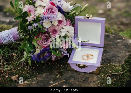 gli anelli di nozze in una scatola vicino al bouquet si trovano sul moncone Foto Stock