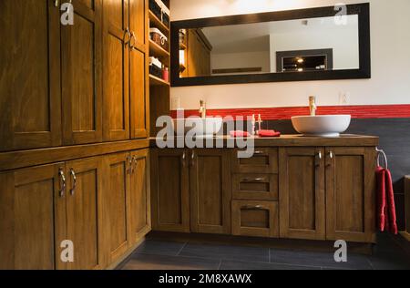 Bagno principale con armadietto in legno marrone con lavandini per ciotola al piano superiore all'interno di una casa in legno in stile scandinavo. Foto Stock