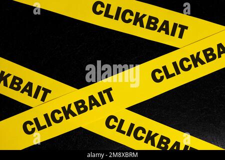 Avviso di truffa Clickbait, attenzione e avviso. Nastro di barricata giallo con parola clickbait su sfondo nero scuro. Foto Stock
