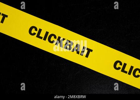 Avviso di truffa Clickbait, attenzione e avviso. Nastro di barricata giallo con parola clickbait su sfondo nero scuro. Foto Stock