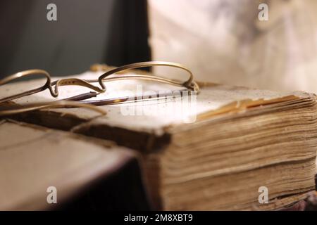 Occhiali antichi, a filo di ferro, poggiati su un vecchio libro. Foto Stock