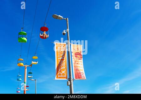 Cartello Santa Cruz Beach Boardwalk. Un manichino caveman cavalca Sky Glider sul Santa Cruz Beach Boardwalk - Santa Cruz, California, USA - 2022 Foto Stock