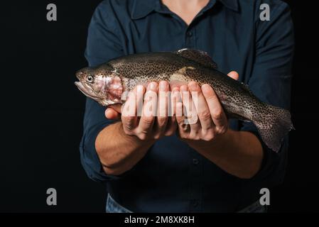 uomo che tiene un primo piano di trota fresca. Pesci rossi vivi Foto Stock