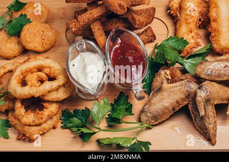 anelli di cipolla, cracker, ali di pollo e altri spuntini alla birra Foto Stock