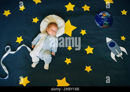 bambino addormentato nella tuta di un astronauta . Concetto di fantasia e sogni del cielo stellato. Vista dall'alto, giacitura piatta Foto Stock