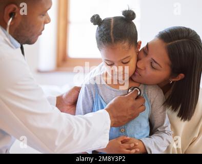 Ragazza piccola triste all'ufficio dei medici. Ragazza malata seduta con la madre mentre pediatra maschile ascoltare il battito cardiaco del petto. Medico di sesso maschile che esamina il bambino con Foto Stock