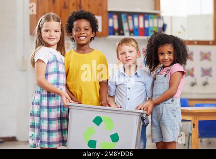 I bambini sono naturalmente curiosi e osservanti. un gruppo di preschoolers che hanno un contenitore di riciclaggio in classe. Foto Stock