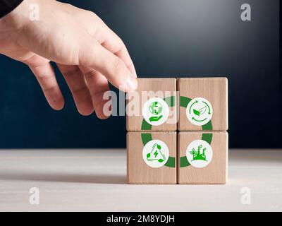 Sviluppo sostenibile, tutela dell'ambiente, energie rinnovabili e concetto di economia circolare. La mano maschile mette i cubi di legno con IC circolare Economy Foto Stock