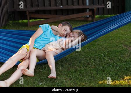 i bambini, fratello e sorella, giocano in giardino su un'amaca. Foto Stock