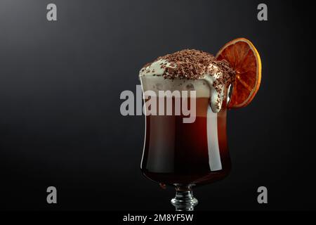 Cocktail al cioccolato con panna montata cosparsa di gocce di cioccolato e guarnita con una fetta di arancia secca. Spazio di copia. Foto Stock
