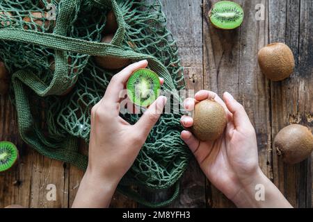 Kiwi in mani femminili, una vista della parte superiore, una donna mette la frutta in una borsa a stringa. Foto Stock