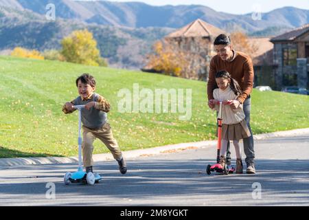 Padre ha portato i bambini a giocare nello scooter Foto Stock