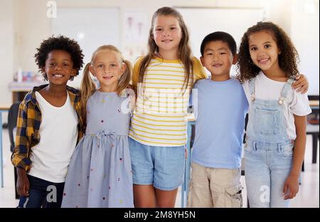 I bambini sono naturalmente curiosi e osservanti. un gruppo di amici in piedi insieme in classe. Foto Stock