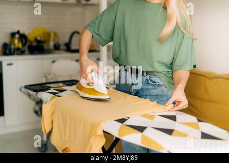 Donna casalinga fa lavori di casa e ferri i vestiti a casa. Foto Stock