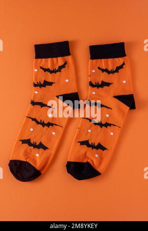 Calzini arancioni con pipistrelli. Costume di abbigliamento per la festa di Halloween. Vista dall'alto della calza vivace e multicolore. Foto Stock