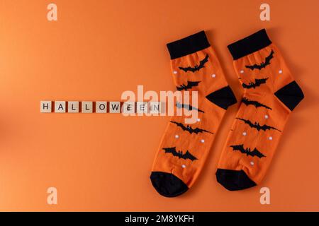 Calzini arancioni con pipistrelli. Costume di abbigliamento per la festa di Halloween. Vista dall'alto della calza vivace e multicolore. Frase in lettere di legno. Parola. Foto Stock