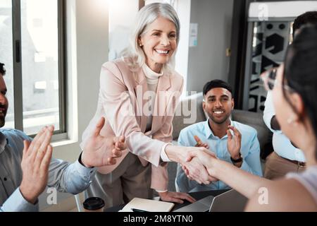 Lo meriti. una donna d'affari matura che stringe le mani con un collega durante una riunione in ufficio. Foto Stock