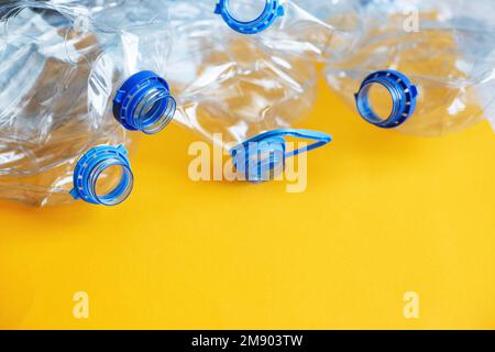 un sacco di plastica vuota rumpled bottiglie usate su uno sfondo giallo. concetto di rifiuti e inquinamento. Foto Stock