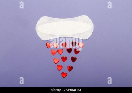 Cuscinetto per l'igiene quotidiana da donna su sfondo viola con cuori rossi. Foto Stock